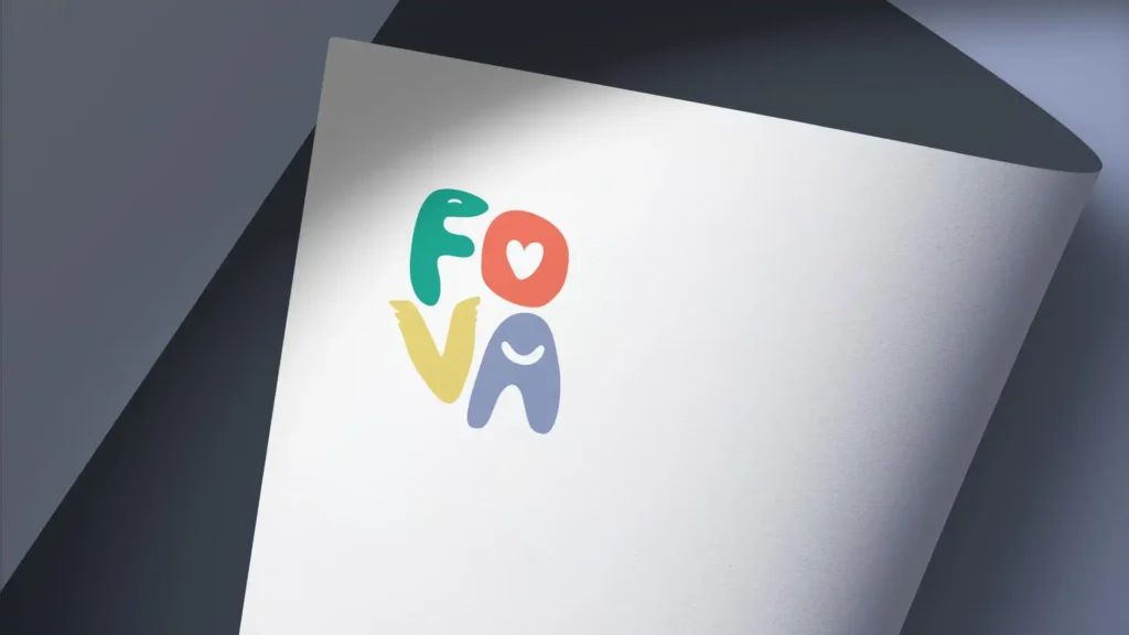 Un papier blanc incurvé avec le mot "fova" écrit en lettres colorées (vert, rouge, jaune, bleu) et un cœur rouge à la place du "o", sur un fond gris foncé.