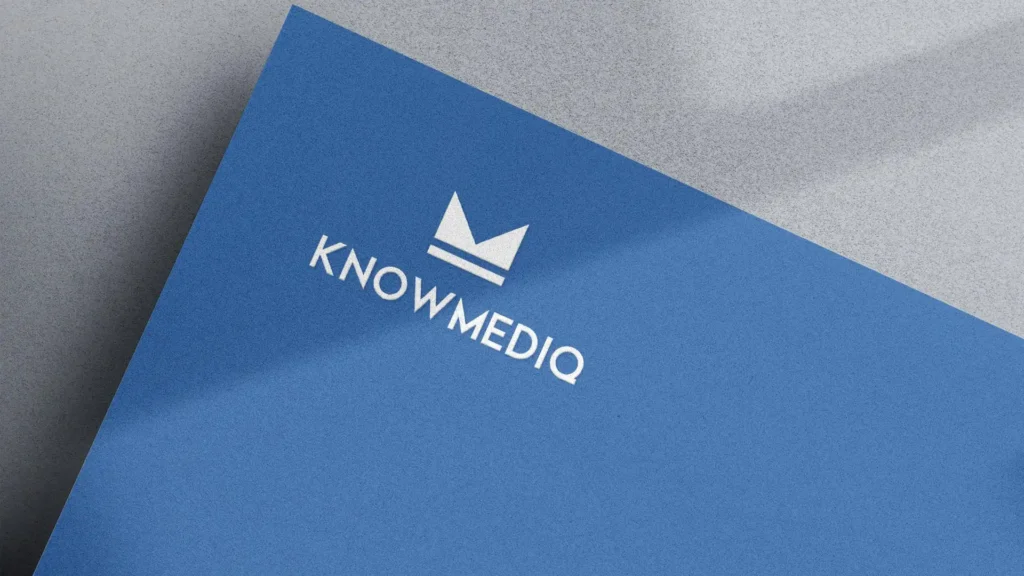 Carte bleue texturée avec le logo et le texte 'KNOWMEDIQ' en blanc, en diagonale sur un fond gris clair.